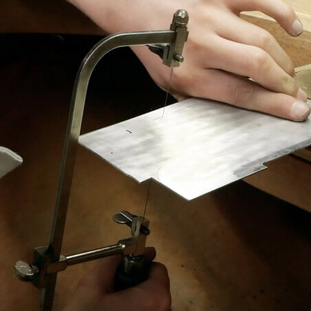 Photo de l'outil tranchant qui découpe une plaque d'argent lors de l'atelier créer son bracelet.