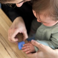 Photo d'une maman et son bébé en train de réaliser une empreinte lors de l'atelier bijou empreinte bébé.