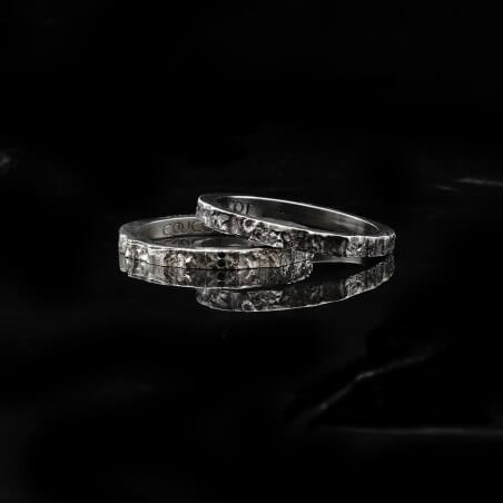 Photo de deux alliances fines diamant blanc modèle Hyperion sur fond marbre noir.