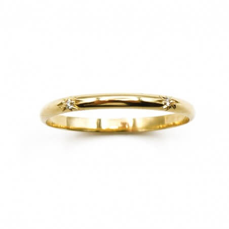 Photo d'une alliance étoile en or jaune 18k sur fond blanc vue de dessus..