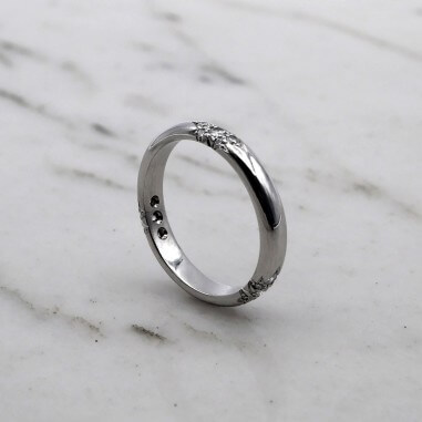 Photo d'une alliance étoile sur fond marbre blanc  vue de 3/4.