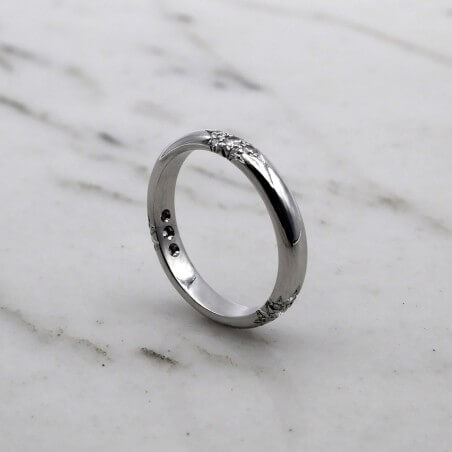 Photo d'une alliance étoile sur fond marbre blanc  vue de 3/4.