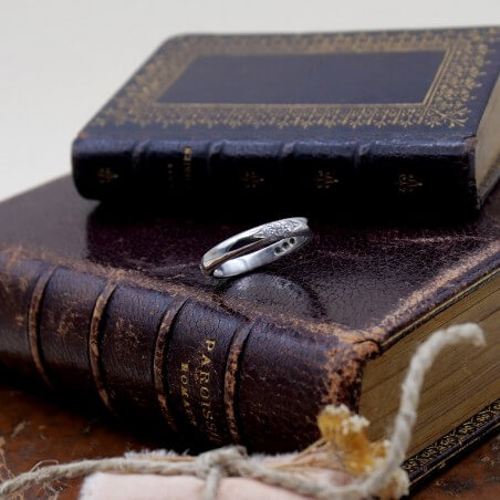 Photo d'une alliance étoile 21 diamants sur fond livre de messe vue de devant.