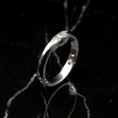 Photo d'une alliance étoile 21 diamants sur fond marbre noir vue de 3/4.