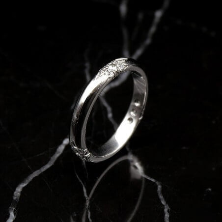 Photo d'une alliance étoile 21 diamants sur fond marbre noir vue de 3/4.