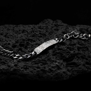 Photo sur fond lave noire de la gourmette homme en argent modèle Hypérion avec détail de la texture.