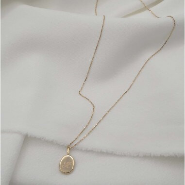 Photo sur fond tissu blanc du pendentif vue arrière avec la gravure créer lors de l’atelier bijou empreinte bébé.