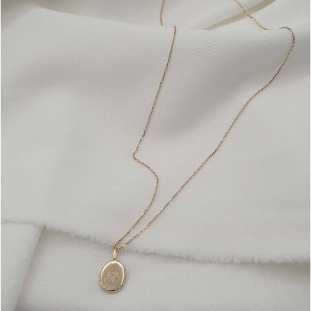 Photo sur fond tissu blanc du pendentif vue arrière avec la gravure créer lors de l’atelier bijou empreinte bébé.