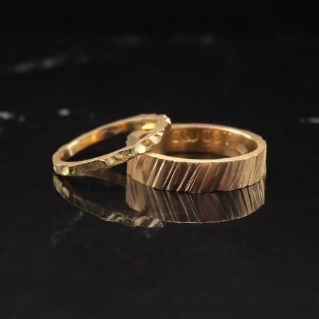 Photo sur fond marbre noir de deux alliances originales en or jaune modèle tungstène.