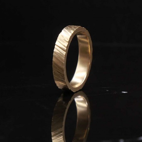 Photo sur fond marbre noir de l’alliance homme en or jaune modèle tungstène vue de trois quart.