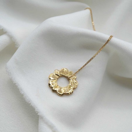 Photo sur fond tissu blanc du pendentif soleil or.