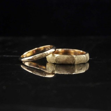 Photo sur fond marbre noir de deux alliances en or jaune fabriquées lors de l'atelier créer son alliance empreinte digitale.