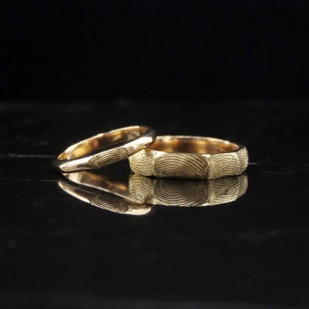 Photo sur fond marbre noir de deux alliances en or jaune fabriquées lors de l'atelier créer son alliance empreinte digitale.