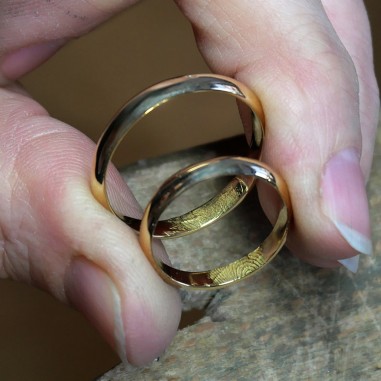 Photo dans les mains de deux alliances en or jaune fabriquées lors de l'atelier créer son alliance empreinte digitale.