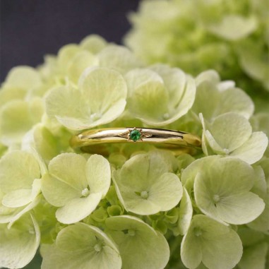 Photo sur fond blanc de l’alliance grenat tsavorite modèle Maïa dans une fleur.