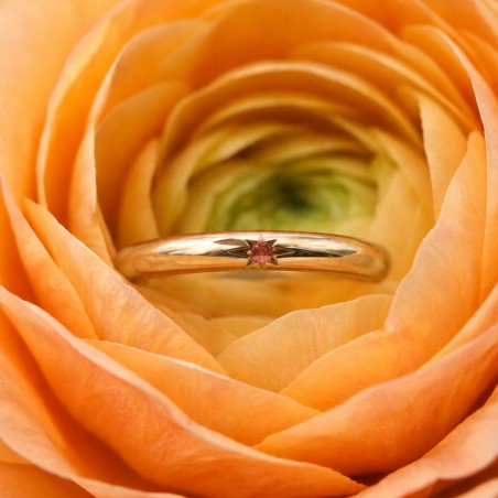 Photo sur fond blanc de l’alliance saphir orange modèle Maïa dans une fleur.