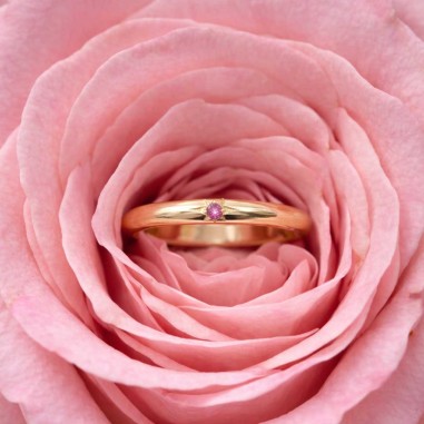 Photo sur fond blanc de l’alliance en saphir rose modèle Électre dans une fleur.